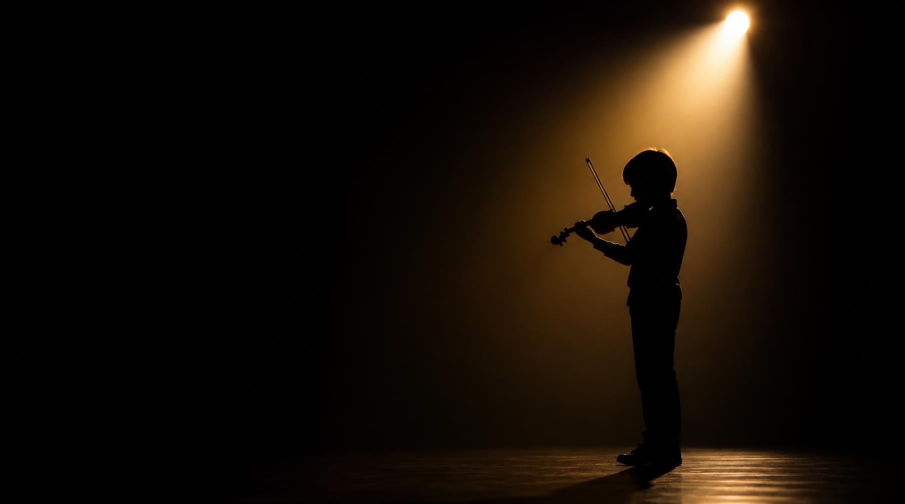 Criança tocando violino sob um feixe de luz